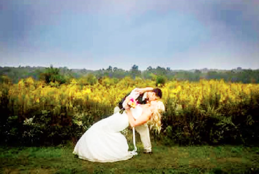 Happily married couple taking a wedding photo in a natural setting.